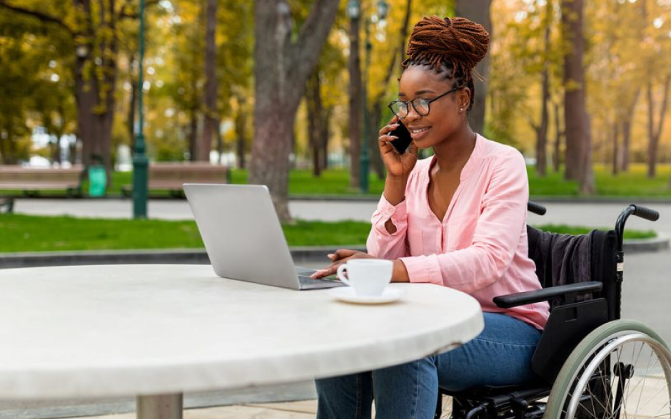 Woman on the phone and her computer at a cafe in wheelchair